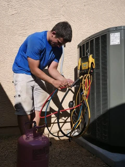 Technician connecting service gauges to a residential air conditioning system