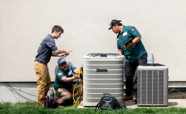 HVAC service professionals inspecting several outdoor air conditioning units