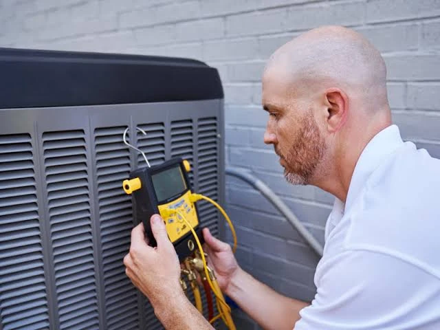 HVAC technician using a diagnostic meter to check an outdoor air conditioning unit
